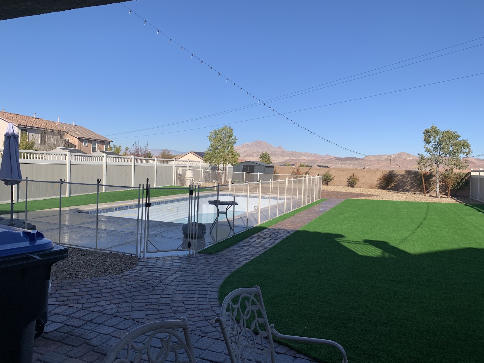 Backyard artificial turf lawn beside pool with paver walkway and mountain views