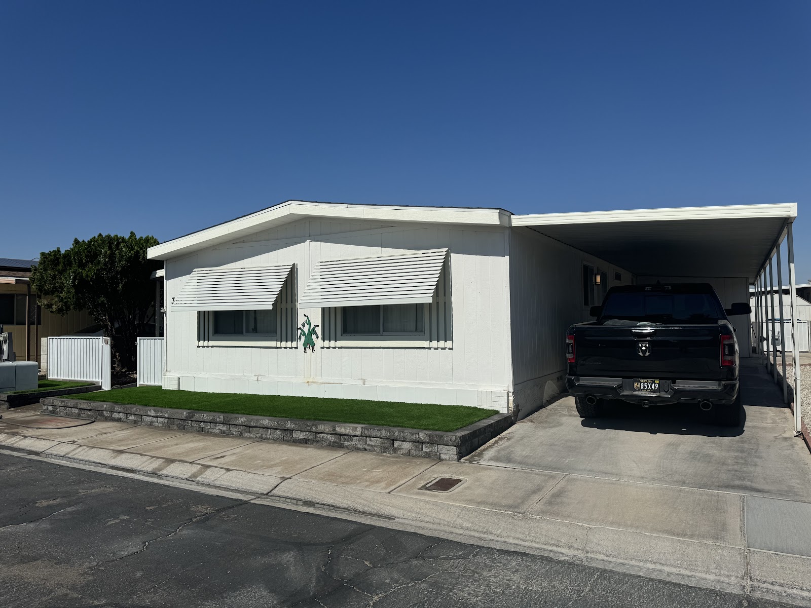 Front of manufactured home with new artificial turf strip and paver retaining edge